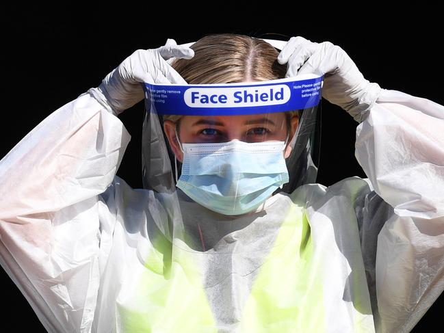 A staff member at a COVID-19 drive through testing station puts on a protective visor in Springfield, in Brisbane’s south-west. Picture: NCA NewsWire/Dan Peled