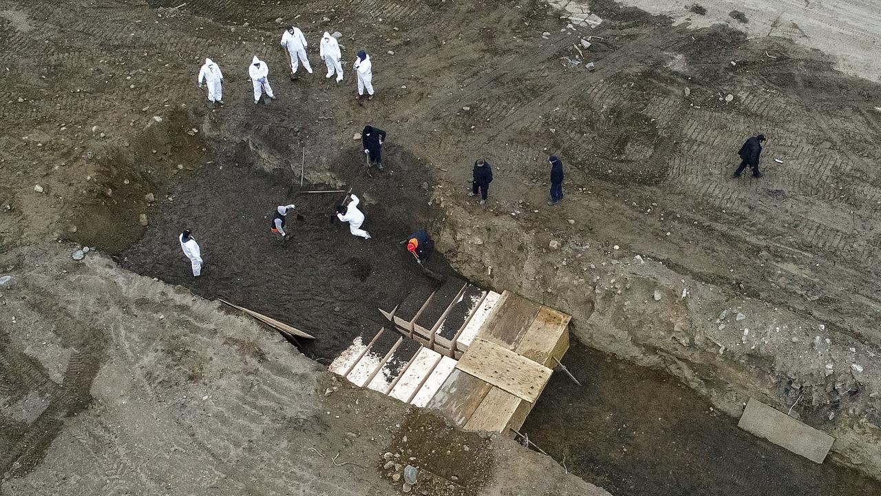 Workers wearing personal protective equipment bury bodies in a trench on Hart Island in the Bronx.