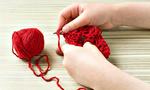 Little girl learns to crochet. Baby hand knit crochet red yarn
