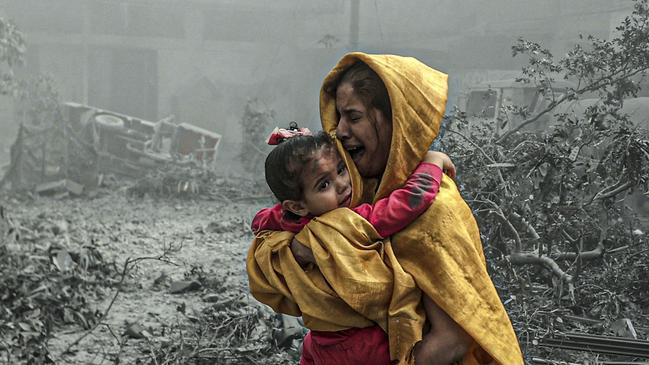 A woman holding a girl following Israeli air strikes on the Ridwan neighbourhood of Gaza City, on October 23. Picture: Getty Images