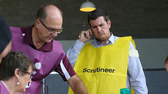 Gaven LNP candidate Sid Cramp( yellow vest) watches vote counting by electoral officials for his seat at Nerang. Picture Glenn Hampson