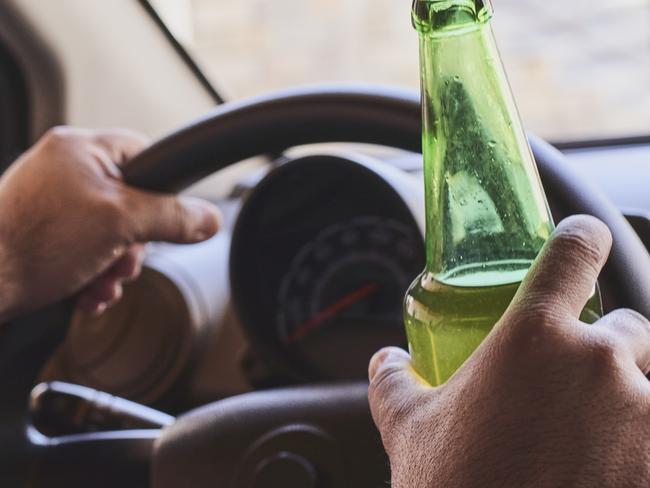 An unrecognizable man drinking beer while driving car. Concepts of driving under the influence, drunk driving or impaired driving. Drink driving generic. Picture: iSTOCK