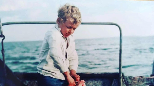 An eight-year-old Jeff Schmucker guts a shark while out on his father's boat.