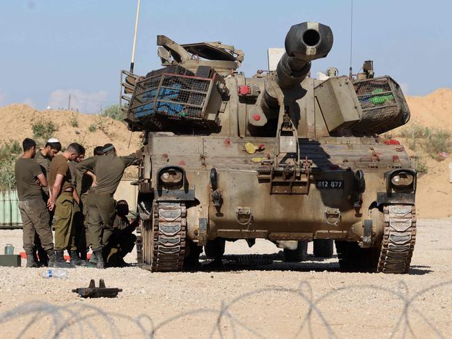 Israeli soldiers provide maintenance to an mobile canon at a position near Israel's border with the Gaza Strip, on May 5, 2025. Israel was issuing orders to call up tens of thousands of reservists ahead of an expanded offensive in Gaza, Israeli media reported on May 3, as Prime Minister Benjamin Netanyahu attacked truce mediator Qatar. (Photo by Menahem KAHANA / AFP)
