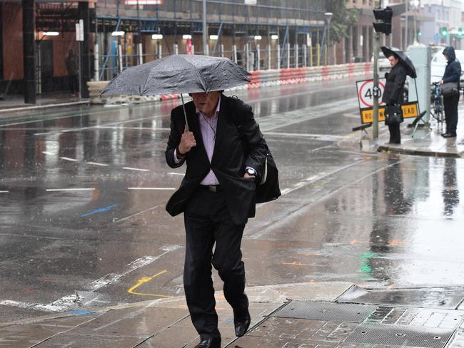 People brave the weather on the way to work in Adelaide today. Picture Campbell Brodie