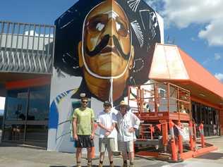 Out There Co. artists Jon Watson, Luke and Bill Gannon create the Harry MiMi mural on Gladstone Road. Picture: Jann Houley