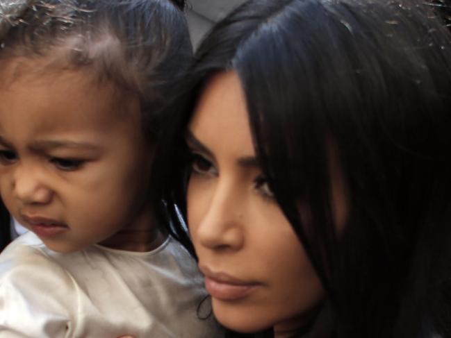 US reality TV star Kim Kardashian carries her daughter North West as she and her husband rapper Kanye West (back) exit a car upon their arrival at the Armenian St. James Cathedral in Jerusalem's Old City for a reported baptism ceremony of their child, on April 13, 2015. AFP PHOTO / AHMAD GHARABLI