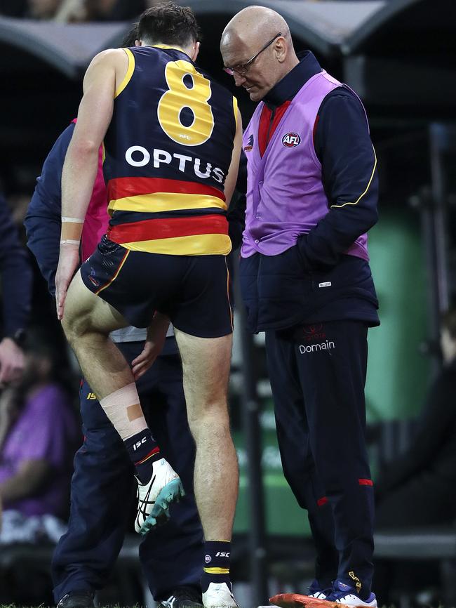 Jake Kelly talks with medical staff on the boundary after getting a corkie in his left calf during the Crows win over Richmond. Picture SARAH REED