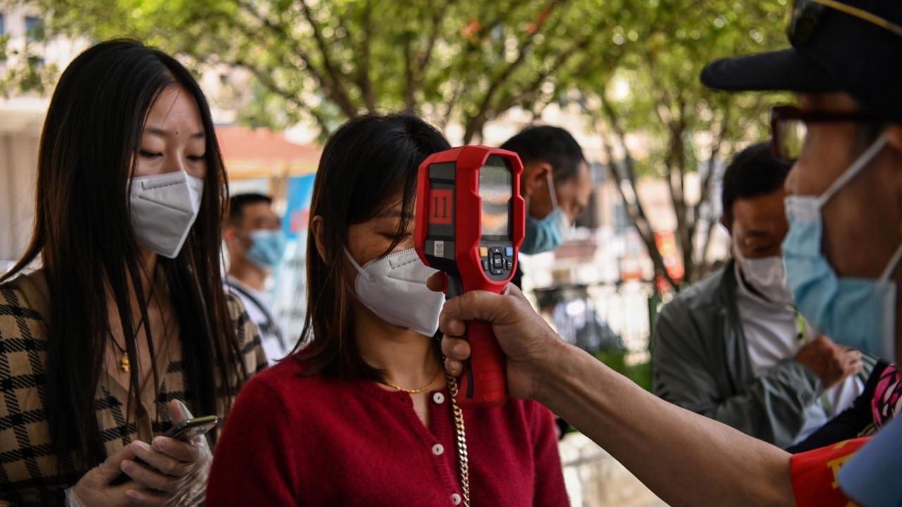 A worker checks passengers body temperatures and a health code on their phones before they take a taxi after arriving at Hankou railway station in Wuhan, Hubei Province. Picture: Hector Retamal/AFP