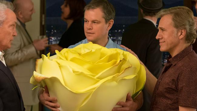 Matt Damon as Paul brings a regulation-size rose to a party thrown by Christoph Waltz (right) in a scene from ‘Downsizing’.