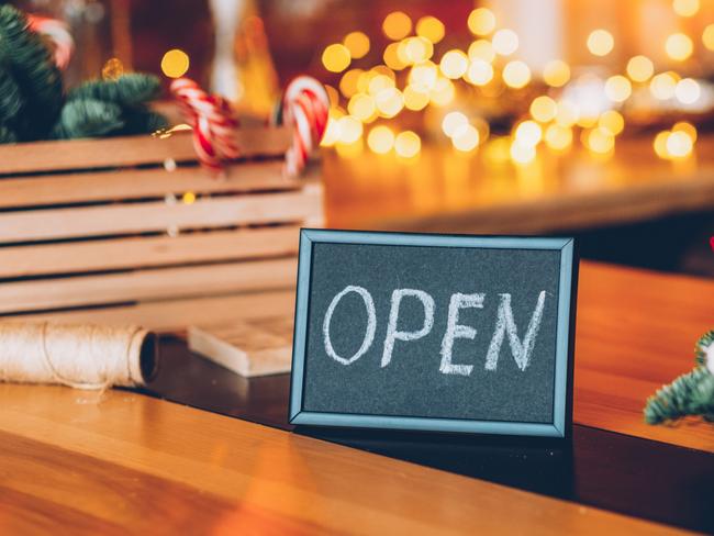 Florist workshop. Christmas decor. Welcoming sign. Frame with open lettering over blur festive interior. Photo: iStock.