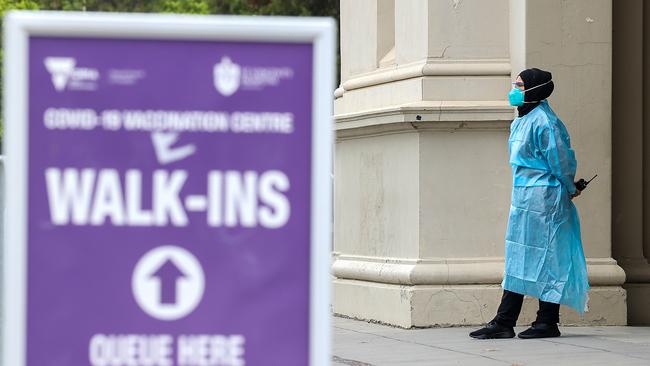 A Victorian health worker waits outside the Royal Exhibition Building for people to get a Covid-19 vaccination. Picture: Ian Currie