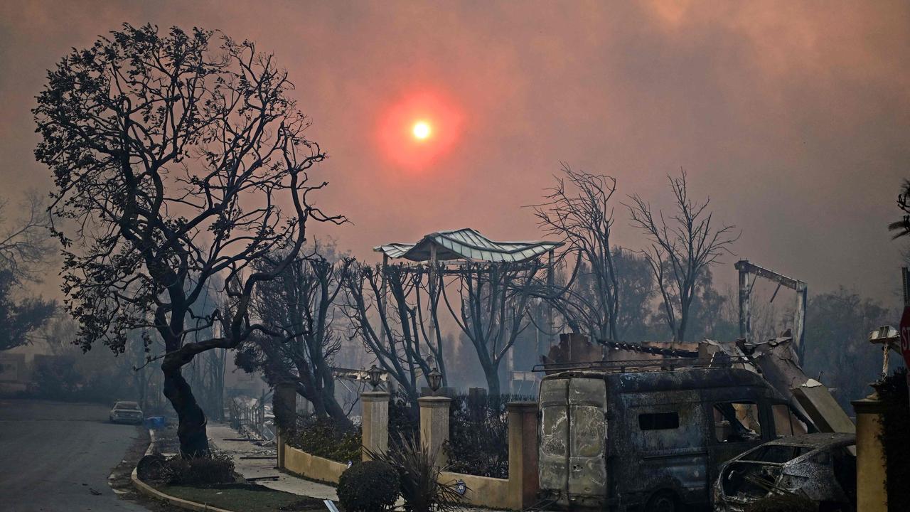 The sun is seen behind smoke above charred structures and vehicles after the passage of the Palisades Fire. (Photo by AGUSTIN PAULLIER / AFP)