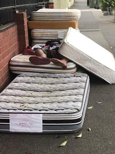 A man sleeps on a pile of discarded mattresses outside the Carlisle St backpackers’ lodge last November.