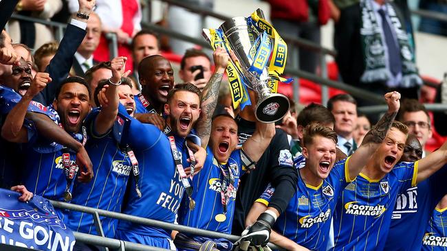 Barry Fuller lifts the trophy with his teammates after Wimbledon won the League Two play-off Final.