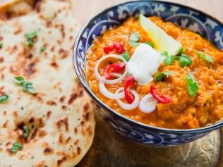 Red Lentils Indian Curry Dal -  spicy dish made from vegetable ingredients  -  legumes, tomatoes, onion, garlic, coconut milk, lime, coriander, chili pepper and spices : cumin seeds, mustard seeds, garam masala, turmeric, cury powder, garlic, nutmeg, cinnamon. Served with fresh Garlic cilantro Naan Bread and Mint Raita.