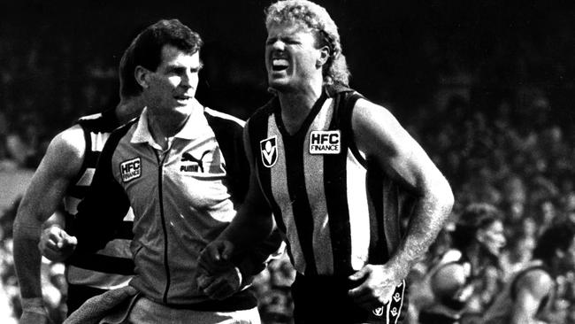 Dermott Brereton is helped from field after being struck by opponent Mark Yeates. Picture: Clive Mackinnon