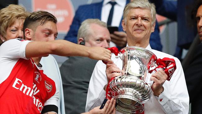 Arsenal's German midfielder Mesut Ozil (L) hands over the FA Cup trophy to Arsenal's French manager Arsene Wenger.