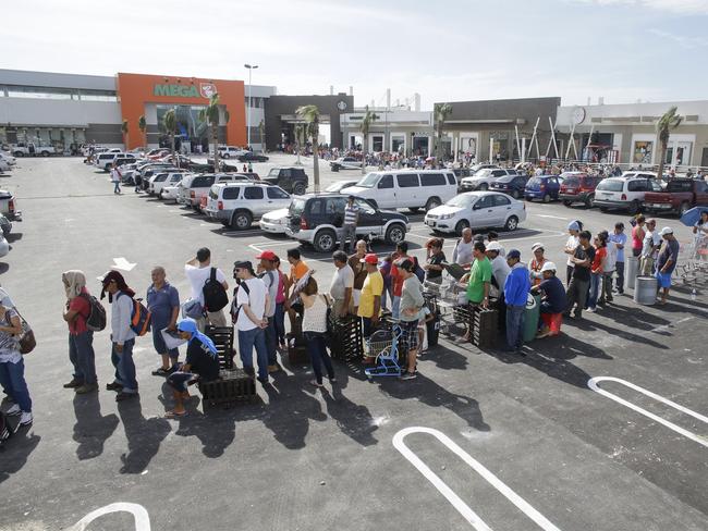 People stand in line to receive free food from a Mega supermarket.