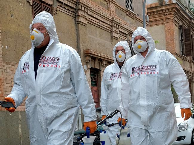 Workers wearing protective outfits sanitize a neighborhood to contain the spread of Covid-19 virus, in Rome,  Saturday, March 28, 2020. The new coronavirus causes mild or moderate symptoms for most people, but for some, especially older adults and people with existing health problems, it can cause more severe illness or death. (Mauro Scrobogna/LaPresse via AP)