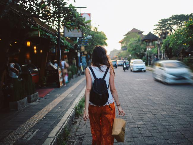 Young woman with a backpack traveling in Bali, Indonesia. She is looking at the street markets that sell clothes and other souvenirs.