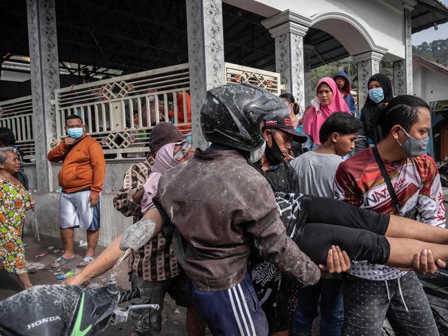 Rescue personnel evacuates a villager in an area covered in volcanic ash at Sumber Wuluh village in Lumajang on December 5, 2021, after the Semeru volcano eruption that killed at least 13 people. (Photo by JUNI KRISWANTO / AFP)