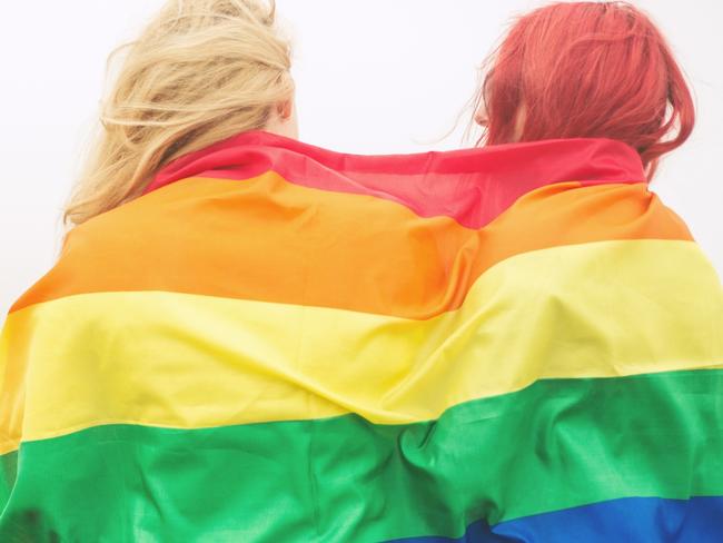 Blonde and redhead woman wrapped in rainbow flag