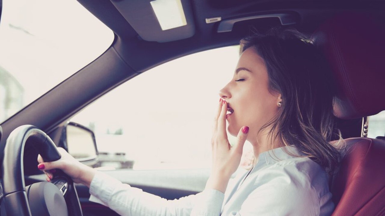 A tired car driver yawning.