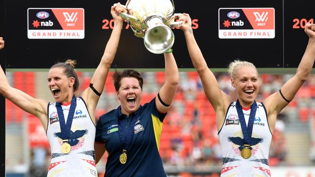 Adelaide coach Bec Goddard lifts the 2017 AFLW premiership cup with co-captains Chelsea Randall (left) and Erin Phillips.