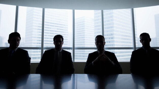 Silhouette row of businessmen sitting in meeting roomMen boardroom business company directors