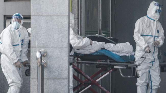 Medical staff members carry a patient into the Jinyintan hospital in Wuhan. Picture: AFP.