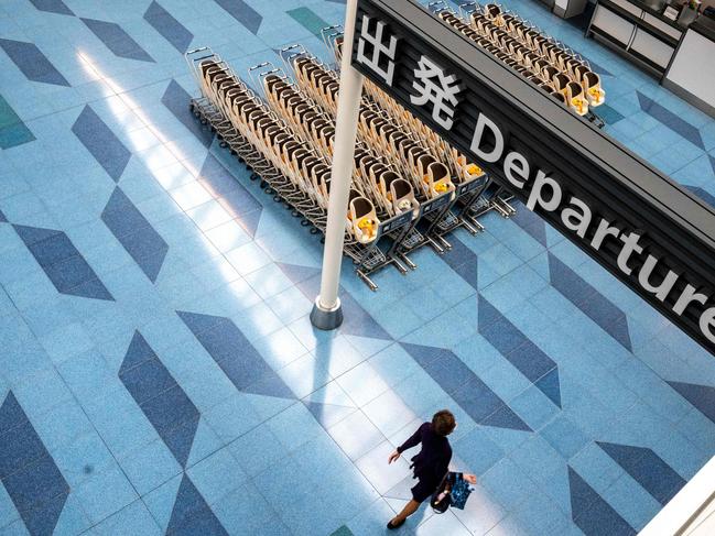 A person walks in an empty departures hall at Tokyo's Haneda international airport on January 25, 2022. - More than 370,000 people are left in limbo by Japan's coronavirus border rules, which bar almost all new arrivals and are the strictest in the G7. (Photo by Philip FONG / AFP) / TO GO WITH Health-virus-Japan-immigration-education,FOCUS by Etienne Balmer and Katie Forster