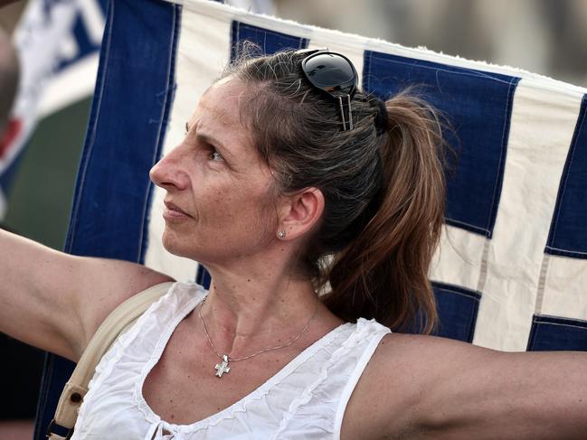 A woman holds a greek flag in front of the Greek parliament in Athens, during an anti-EU demonstration calling for a 'No' to any agreement with the creditors, on July 13, 2015. Eurozone leaders struck a deal on July 13 on a bailout to prevent debt-stricken Greece from crashing out of the euro forcing Athens to push through draconian reforms in a matter of days. AFP PHOTO / LOUISA GOULIAMAKI