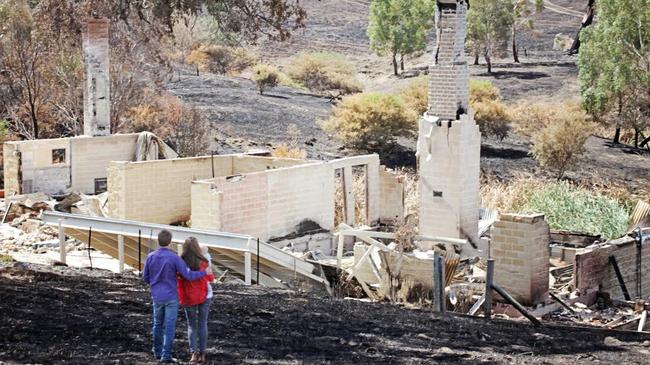 Scott Pape and his wife Liz survey what was left standing after the bushfire hit their property.