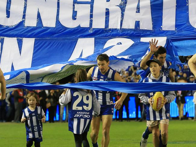 Brent Harvey runs through the banner with his children before the game. Picture: Wayne Ludbey