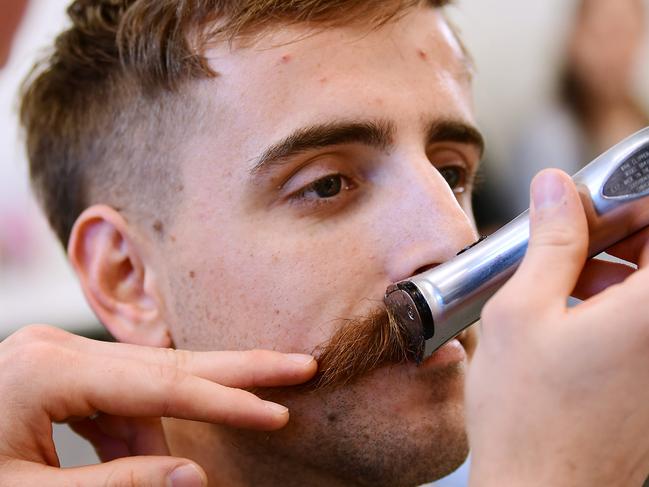 Crows Jordan Gallucci has his moustache shave off by barber Grant Freeman at The Fellow Barber at Henley Beach Sunday,September,29,2019.(Image AAP Mark Brake)