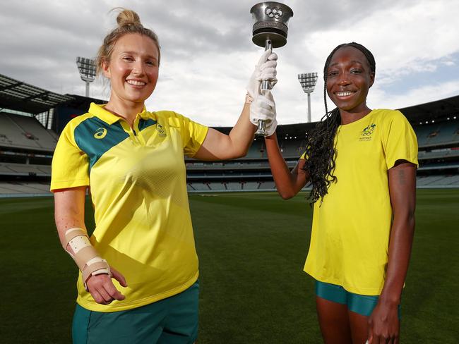 MELBOURNE.  18/11/2021. 65th anniversary of the 1956 olympics at the MCG. Current Olympians Milly Tapper (table tennis) and Bendere Oboya (athletics) with the 1956 Olympic Torch  ...  Photo by Michael Klein.