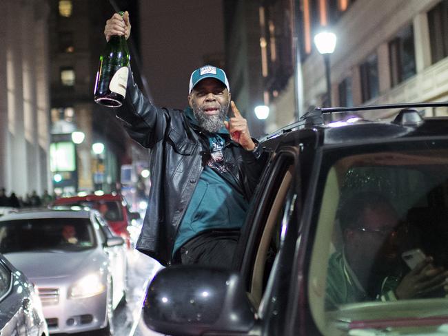 A Philadelphia Eagles fan holds a champagne bottle out a car window.