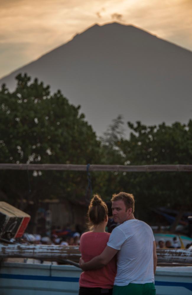 Tourists watch a prayer as Mount Agung volcano is seen in the background at Amed beach in Karangasem on the island of Bali on September 27, 2017. Picture: Bay Ismoyo