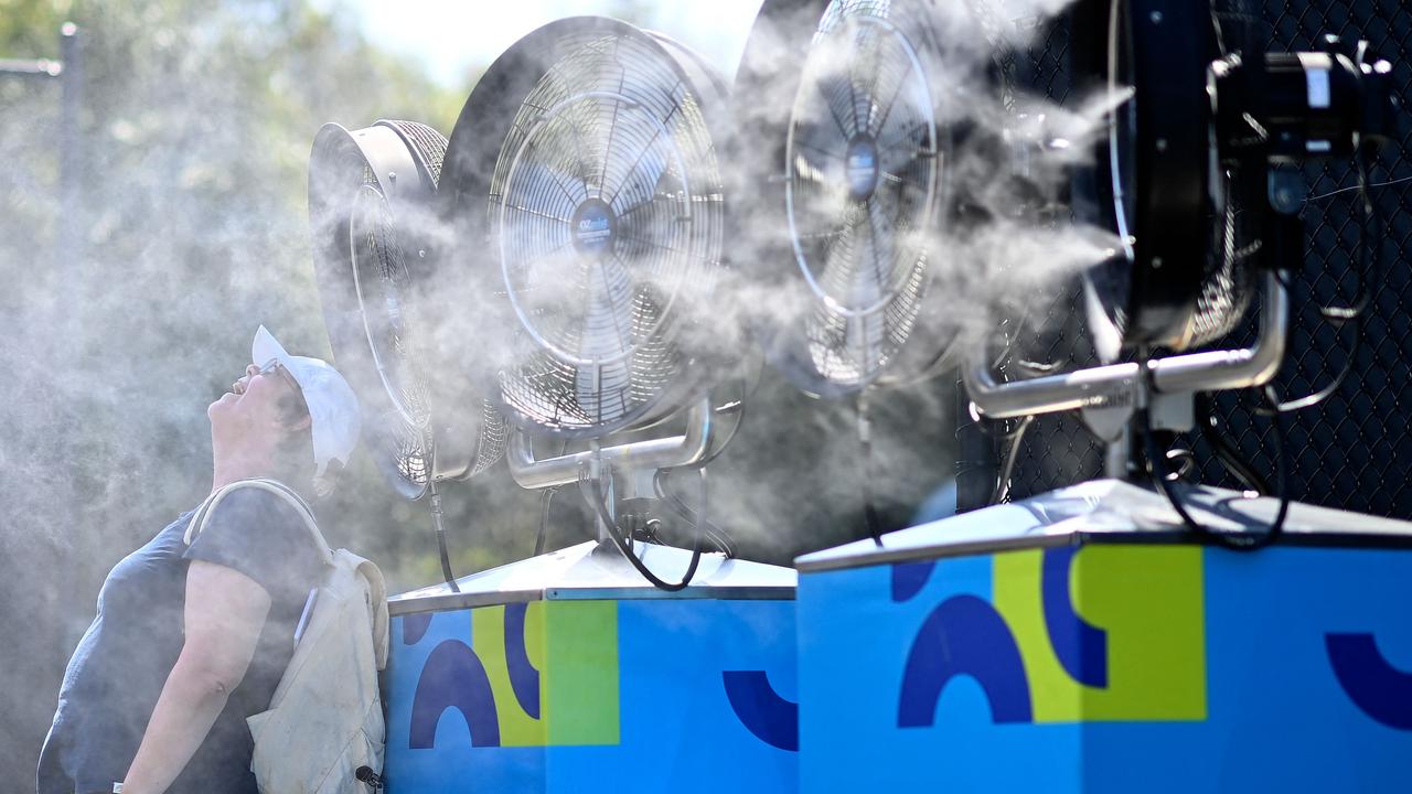 A woman cools off from the heat in front of mist cooling fans at the Melbourne Park.