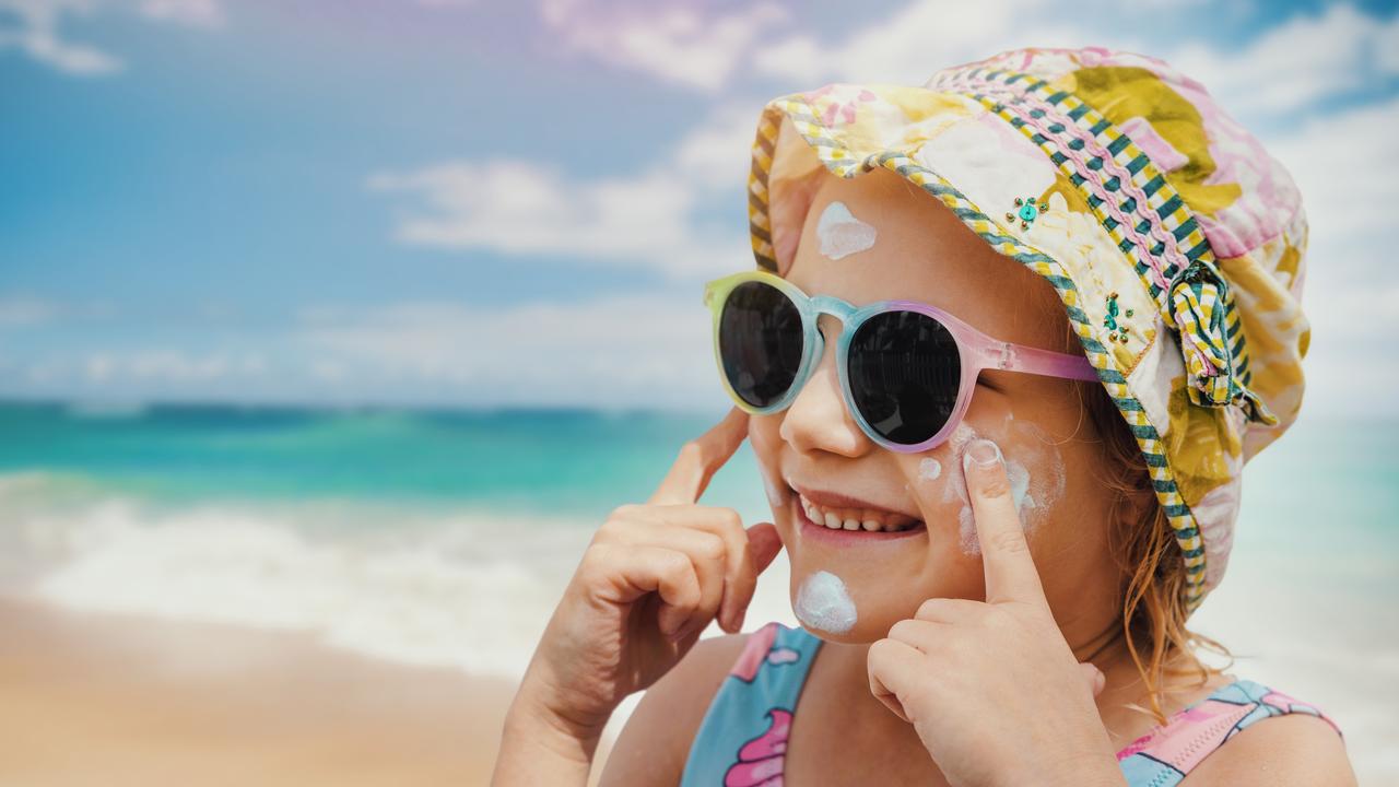 A girl uses a hat, sunglasses and sunscreen for sun protection.