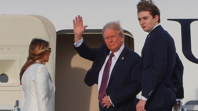 US President-elect Donald Trump waves beside his wife Melania Trump and their son Barron as they board a US government aircraft at Palm Beach International Airport to head to Washington DC. (Photo by Eva Marie UZCATEGUI / AFP)