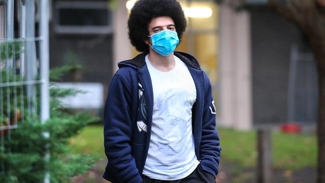 A man leaves the North Melbourne housing estate wearing a mask. Picture: Ian Currie