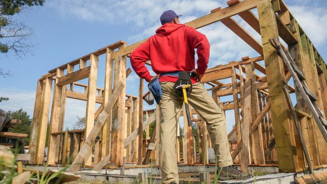 Developing Queensland - roofer, carpenter working on roof structure at construction site.