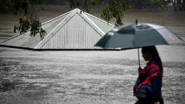 A woman walks past a flooded park along the Nepean River in Penrith, western Sydney, on Sunday. Picture: AFP