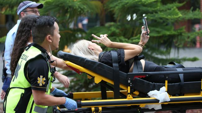 A girl takes a selfie as she is taken away on a stretcher outside the Rolling Loud Festival. Picture: Damian Shaw