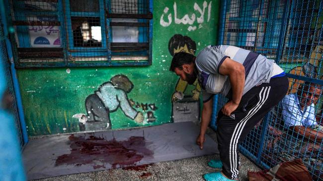 A Palestinian man checks a blood stained mattress at the school.