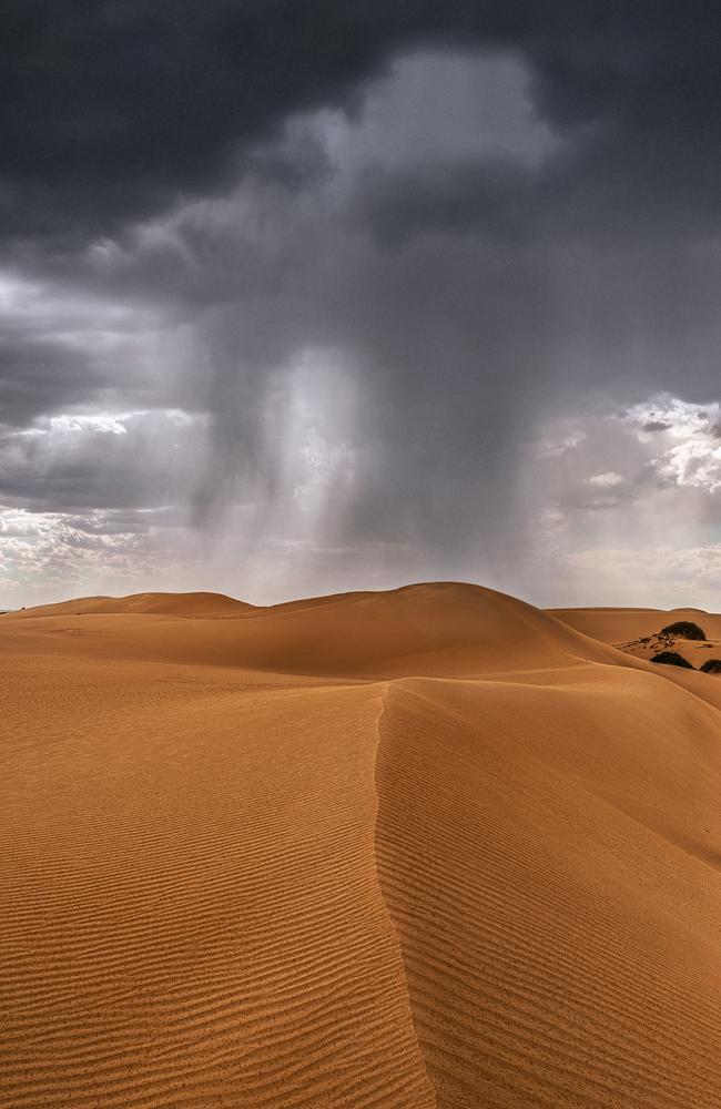 Staggering ... Rain over sand dunes, near Mungo, NSW. Picture: Tony Middleton