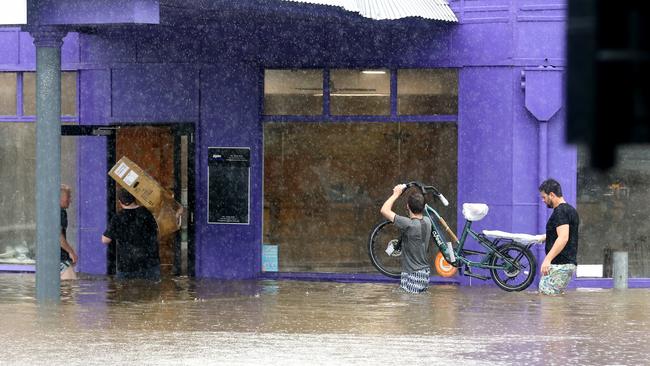 Epic staff rescue shop goods from the rising water. Picture: Steve Pohlner