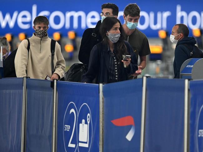 Passengers wearing face masks or covering due to the COVID-19 pandemic, queue at a British Airways check-in desk at Heathrow airport, west London, on July 10, 2020. - The British government on Friday revealed the first exemptions from its coronavirus quarantine, with arrivals from Germany, France, Spain and Italy no longer required to self-isolate from July 10. Since June 8, it has required all overseas arrivals -- including UK residents -- to self-quarantine to avoid the risk of importing new cases from abroad. (Photo by DANIEL LEAL-OLIVAS / AFP)